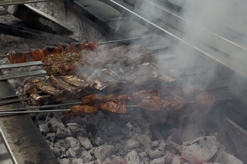 Skewers cooking on the long charcoal mangal at Kelebek Ocakbaşı, steam rising