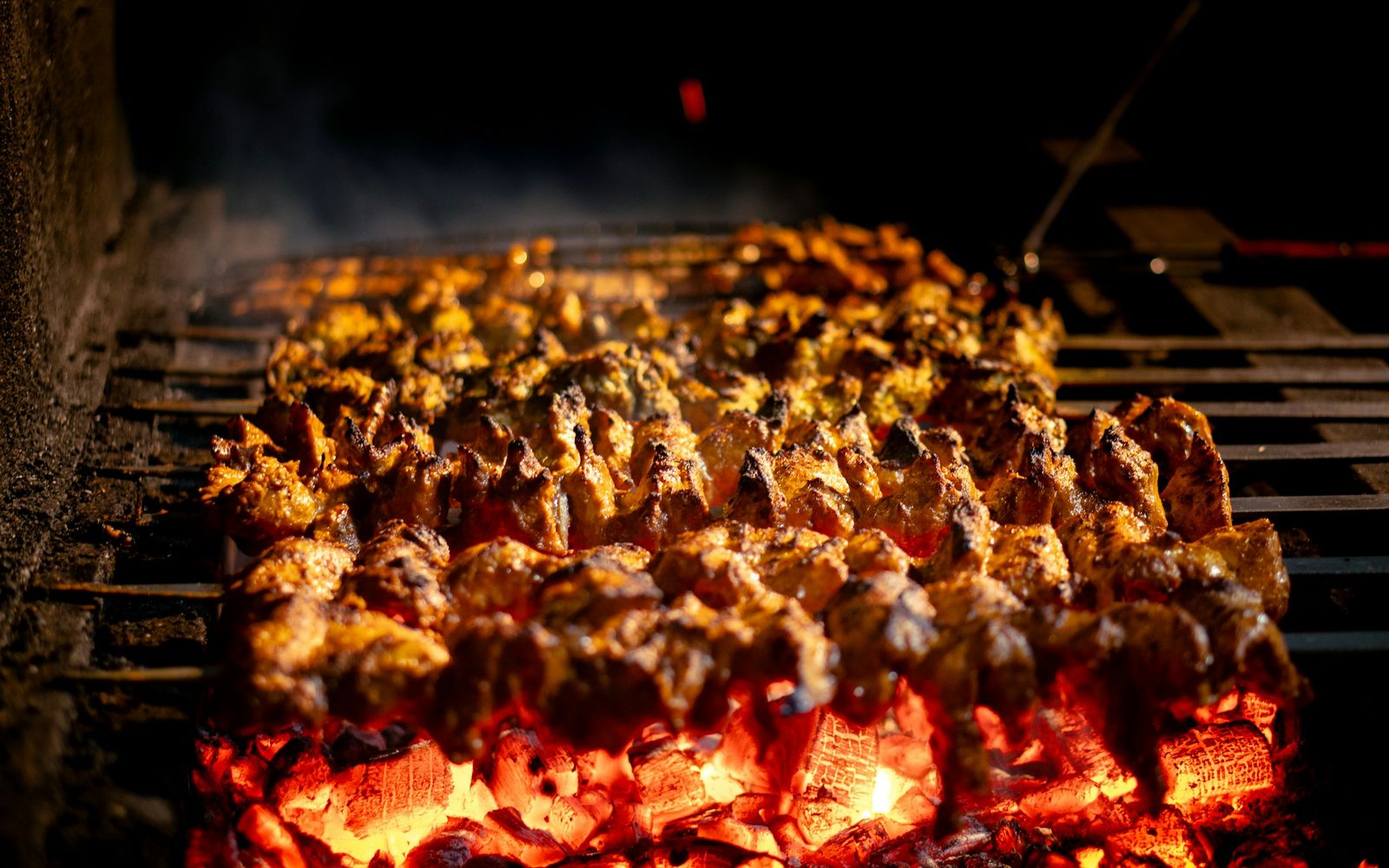 Meat skewers cooking over glowing charcoal